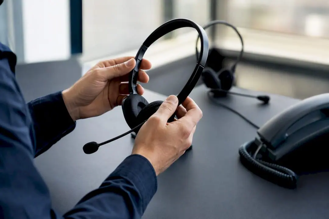 Hände justieren ein Headset am Schreibtisch