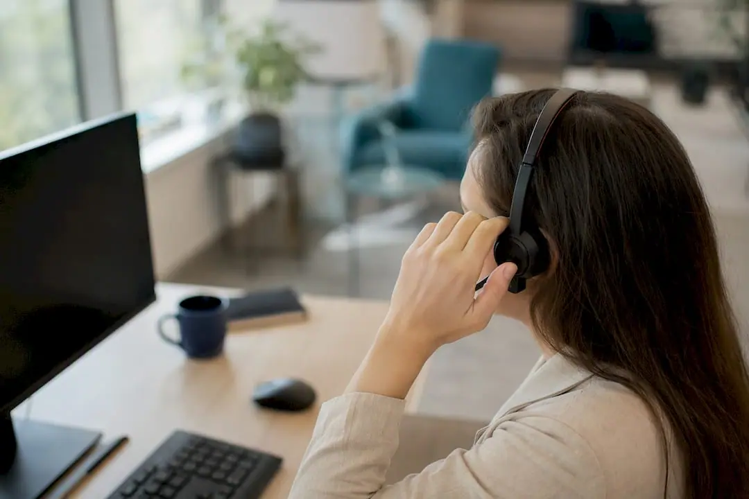 Eine Hand richtet das Headset eines Mitarbeiters im Callcenter.