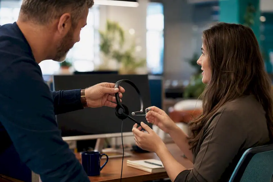 Im Callcenter-Coaching wird das Headset von einem Mitarbeitenden an den nächsten weitergegeben, um praktische Erfahrungen direkt am Arbeitsplatz zu ermöglichen.