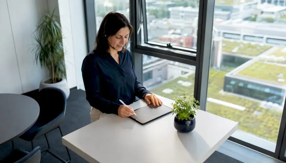 Mitarbeiterin im Kundenservice telefoniert am Schreibtisch mit Headset